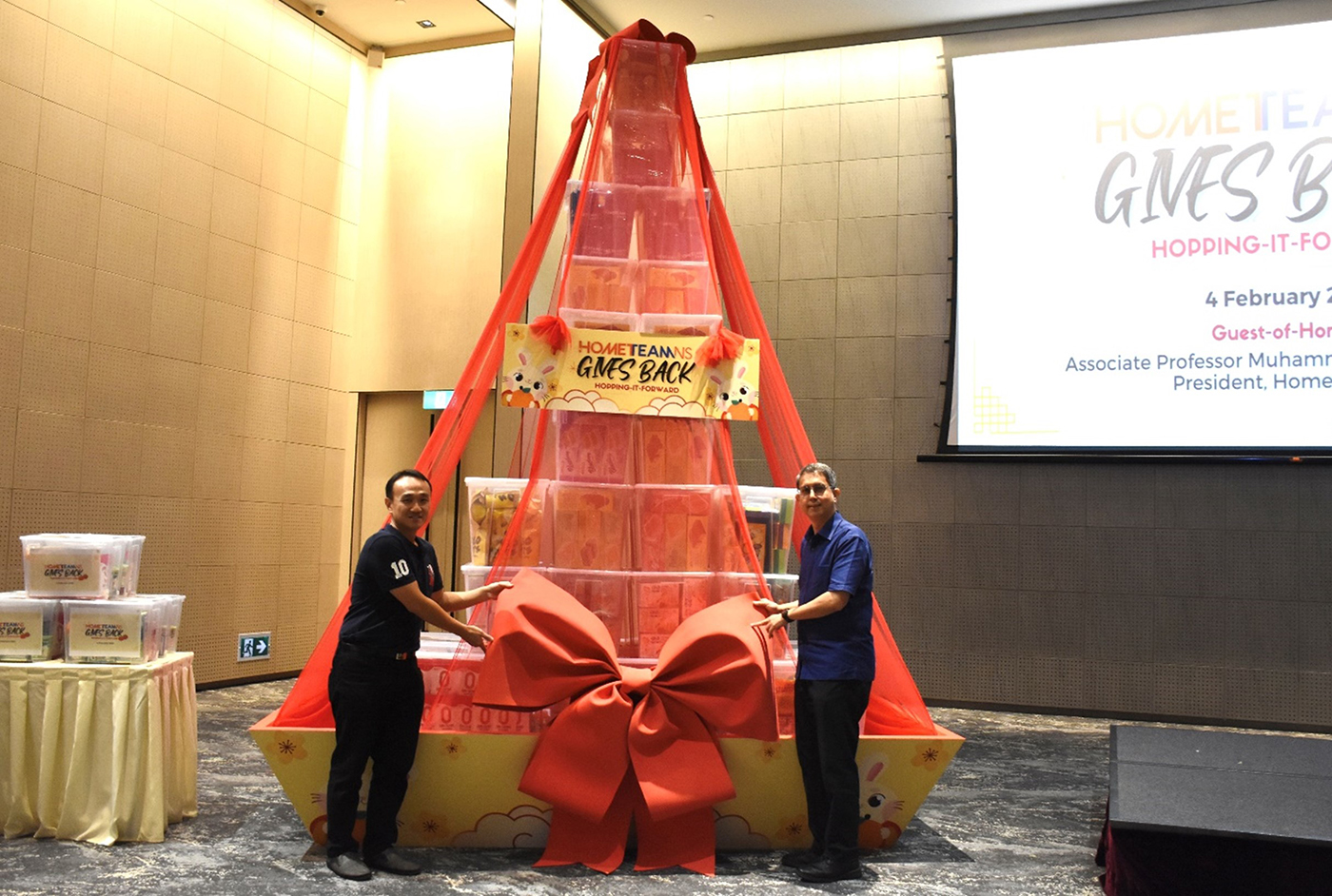 COL (NS) Sim Meng San, Chairman of the HomeTeamNS Khatib Executive Committee, and Associate Professor Muhammad Faishal Ibrahim, President of HomeTeamNS placing the ribbon on the hamper.