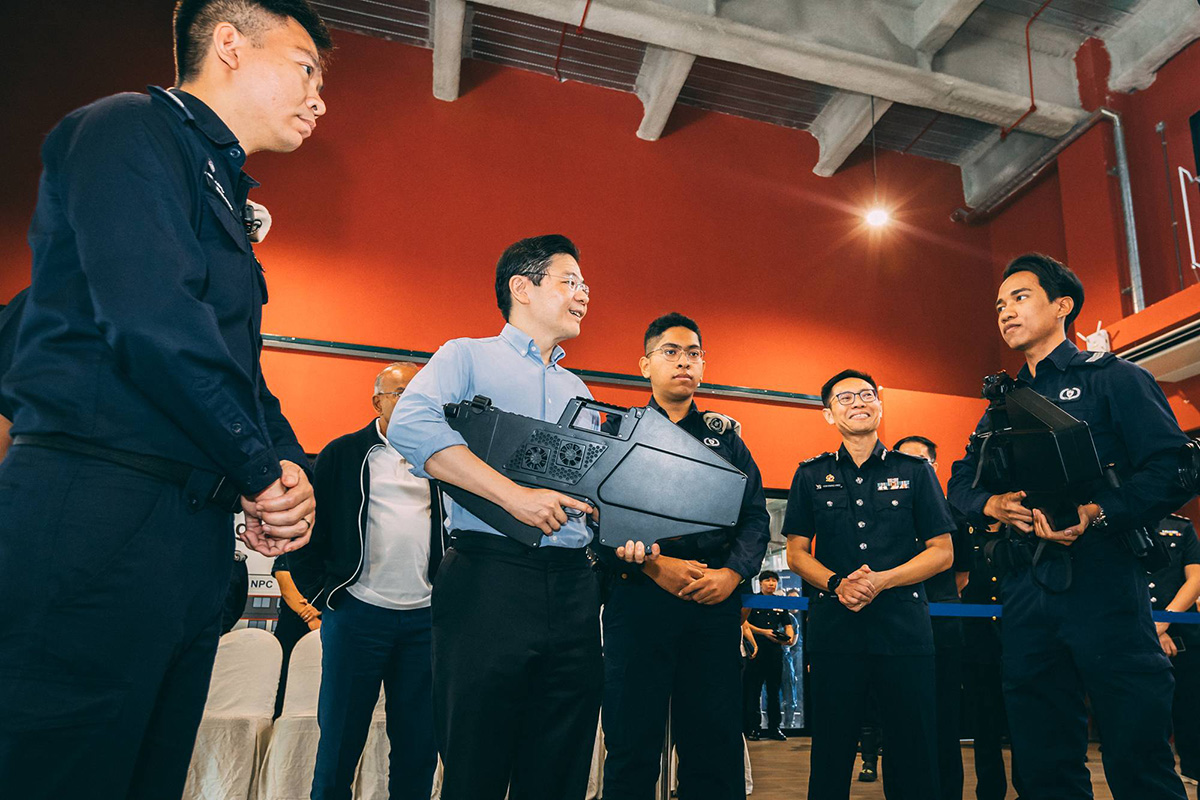 PM Wong speaks with ProCom PNSF Special Constable Sergeant Muhammad Noor Affif Bin Hasanuddin (right) about the Radio Frequency-based Jammer Gun.